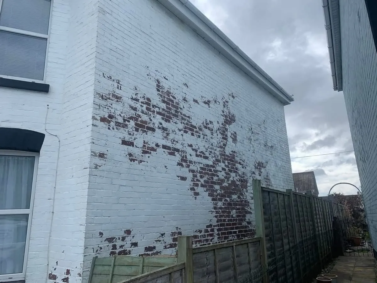 Peeling paint on a brick wall before redecoration in Ottery St Mary
